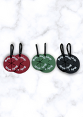 Three round luggage tags in red, green, and black on a marble surface