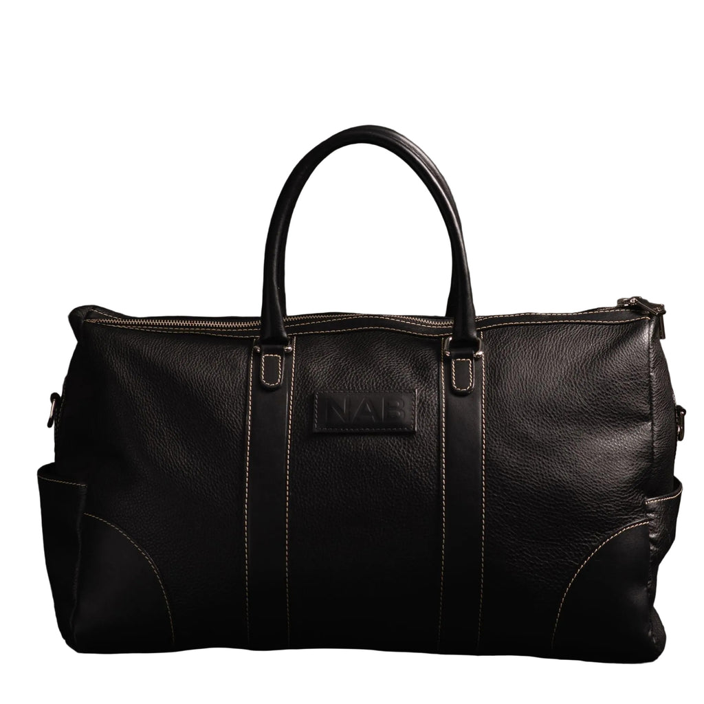 "The Shield Duffle in black — handcrafted full-grain leather duffle bag with rolled leather handles, YKK zipper, and side pockets, made in Canada by NAB Leather"
