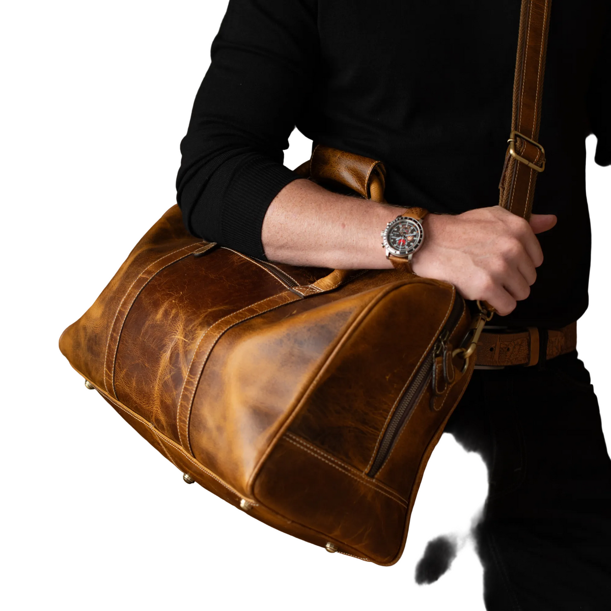 "Close-up of someone gripping the top handle of The Wayfarer Bag — cognac full-grain leather duffle with brass hardware by NAB Leather"
