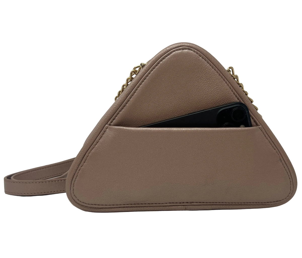 Back view of the Kiana triangular platinum pink leather evening bag, showing a black smartphone sliding into the integrated exterior cell phone pocket.