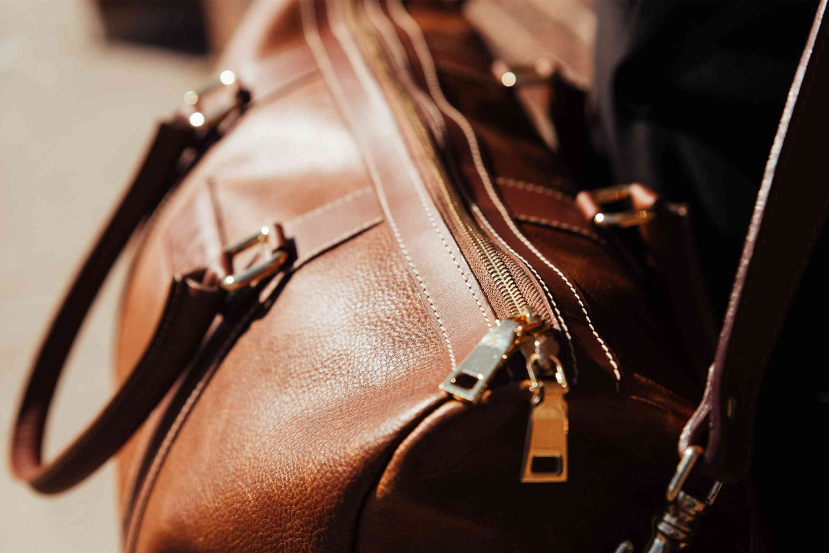 "Close-up of rolled leather handles and hardware on The Shield Duffle in cognac — vegetable-tanned full-grain leather detail by NAB Leather"