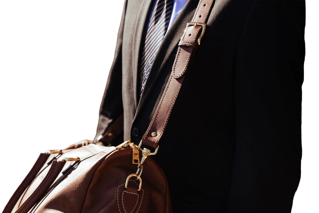 "The Shield Duffle in cognac worn over the shoulder with detachable leather strap — full-grain leather travel bag made in Canada by NAB Leather"