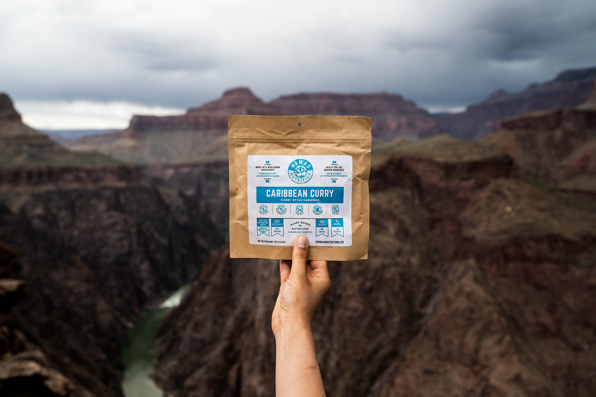 Hand holding a package of 'Caribbean Curry' against a canyon background