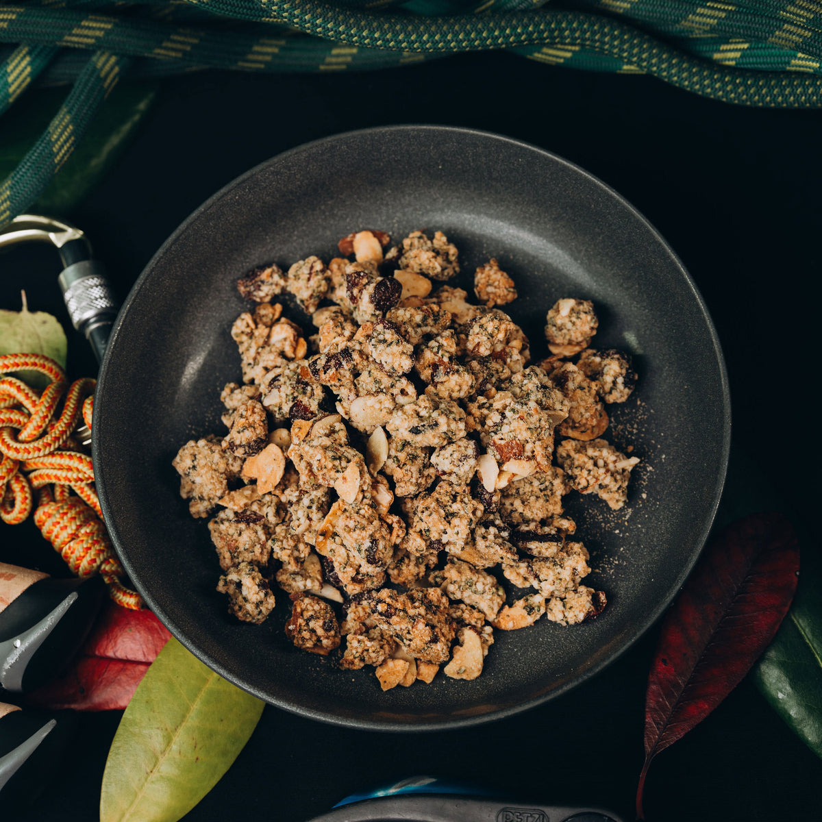 Fried ground meat in a black pan on a dark background with green leaves.