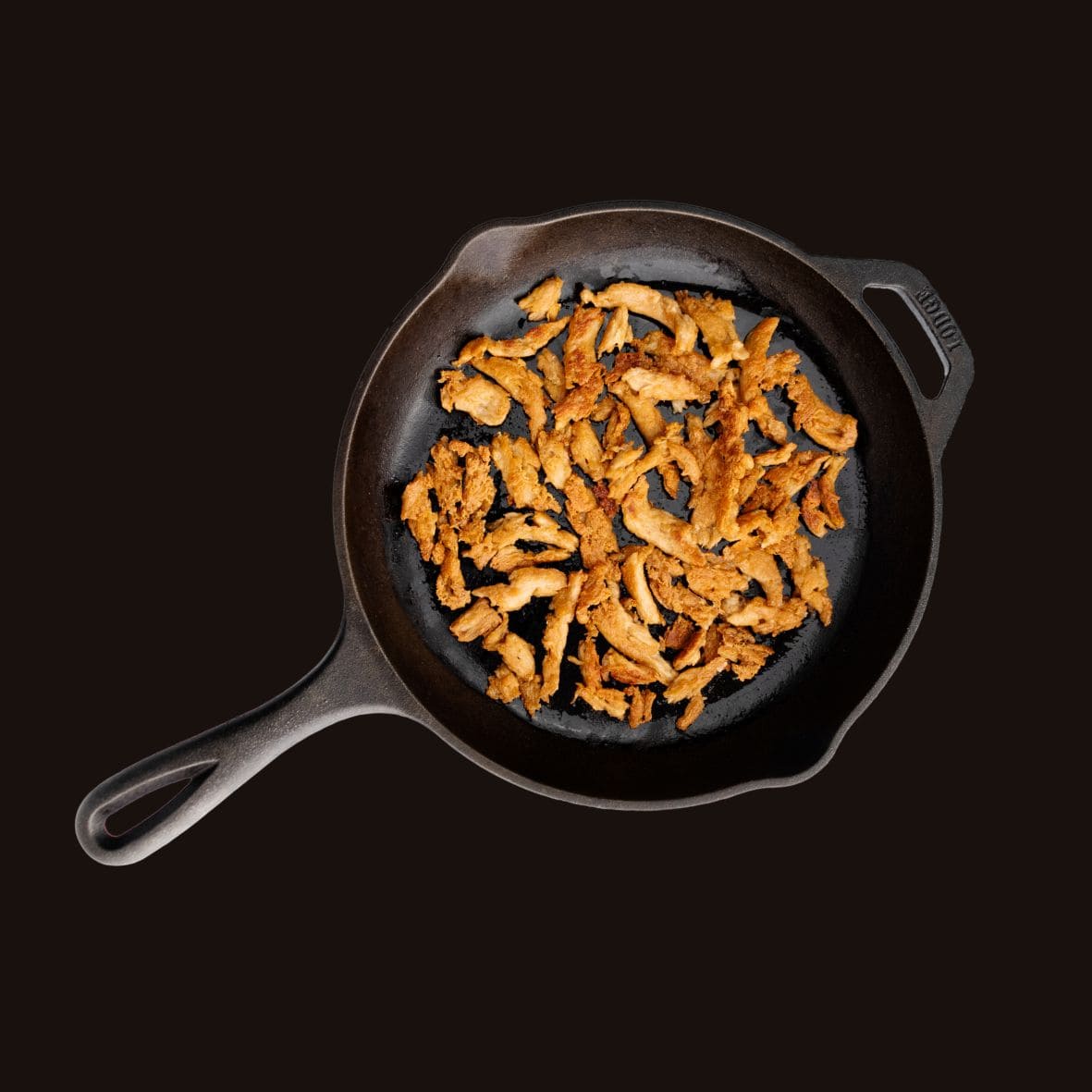 Fried chicken strips in a cast iron skillet on a black background