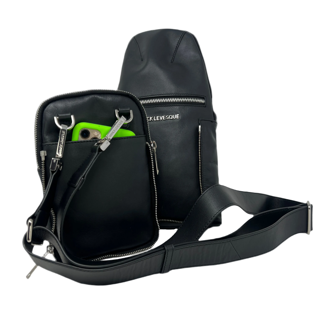 The detached front pouch of the Gabriel 3-in-1 black travel bag being used independently as a small crossbody phone bag with an integrated shoulder strap, a bright green smartphone peeking out of the pocket, and the main bag body standing behind it.